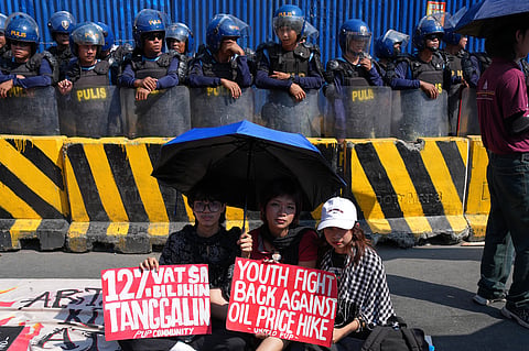 Protesters hold slogans beside police during a rally by transport workers and activists protesting the rise in oil prices on March 27, 2026, near the Malacanang presidential palace in Manila, Philippines.