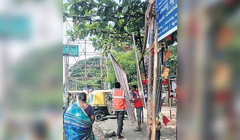Workers removing a banner as part of the Bengaluru East Corporation's special enforcement drive.