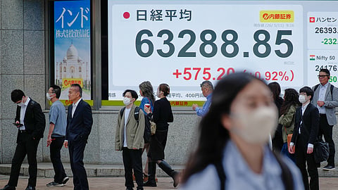 People stand in front of an electronic stock board showing Japan's Nikkei index at a securities firm Monday, May 11, 2026, in Tokyo.
