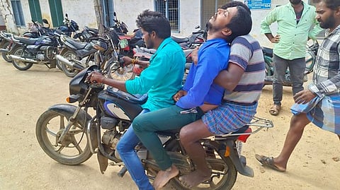 Friends carry the man's body on a motorcycle after auto drivers refuse transport.