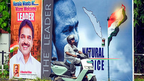 A man rides past posters supporting KC Venugopal and VD Satheesan near the Congress headquarters, in Thiruvananthapuram, Friday, May 8, 2026.