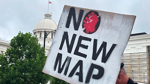A demonstrator holds up a sign outside the Alabama Statehouse in Montgomery, Ala., on Thursday, May, 7 2026.