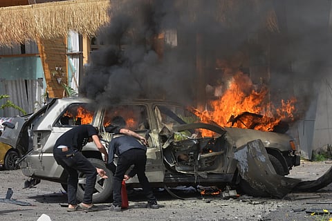 A person is seen inside a burning vehicle as men attempt to put out the fire after an Israeli airstrike hit a car in the coastal town of Barja, south of Beirut, Lebanon, Wednesday, May 13, 2026.