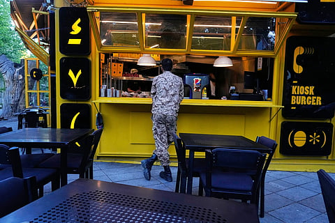 A Revolutionary Guard soldier stands at the counter of a fast food restaurant in northern Tehran, Iran, Sunday, May 10, 2026.