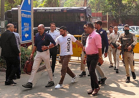 National Investigation Agency (NIA) officials bring wanted narco-terrorist Iqbal Singh alias Shera, in white, to produce before the Patiala House court, after his successful extradition from Portugal, in New Delhi, Wednesday, May 13, 2026