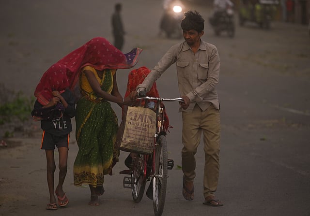 Commuters make their way through a dust storm, in Prayagraj, Uttar Pradesh, Wednesday, May 13, 2026.