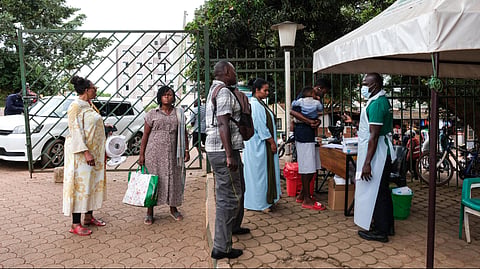People wait to have their temperature taken in front of Kibuli Muslim Hospital in Kampala, Uganda, Saturday, May 16, 2026.