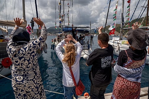 People wave to boats belonging to the Global Sumud Flotilla, carrying activists and humanitarian aid, depart for Gaza from the port of Marmaris, Turkey, Thursday, May 14, 2026, in an attempt to break the Israeli naval blockade.