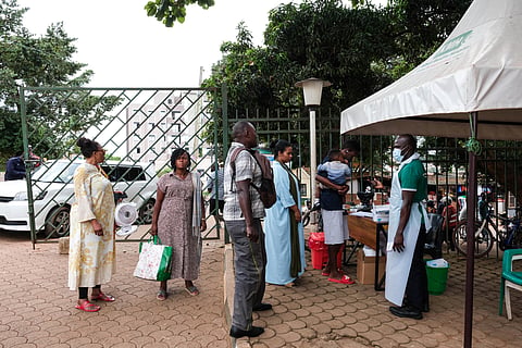 People wait to have their temperature taken in front of Kibuli Muslim Hospital in Kampala, Uganda, Saturday, May 16, 2026.