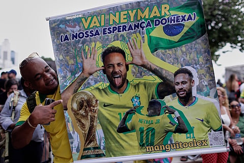 A fan poses with a poster of Brazilian soccer player Neymar, reading in Portuguese "Go Neymar, our hope for a sixth World Cup title"