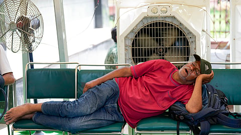 Man takes a nap in front of the cooler taking shade from the scorching sun.