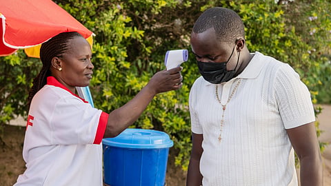 A health worker uses a thermometer to screen a man by the roadside in Bunia, Congo, Tuesday, May 19, 2026.