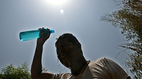 A man pours water over his head to beat the scorching heat as temperatures soar during the ongoing heatwave in Hyderabad