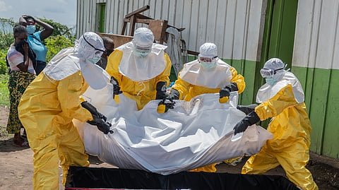 Red Cross workers carry the body of a person who died of Ebola into a coffin at a health center in Rwampara, Congo, Wednesday, May 20, 2026.