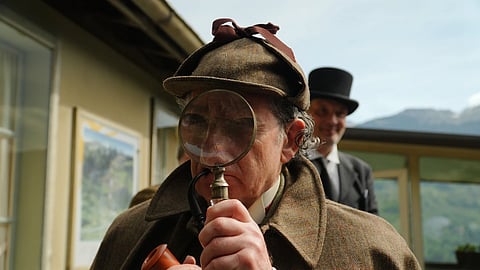 Philip Porter, playing Sherlock Holmes, looking through a magnifying glass during an event recreating the fateful confrontation between Sherlock Holmes and Professor Moriarty by the members of the Sherlock Homes Society of London, at the Reichenbach Falls, Switzerland, May 3, 2026.