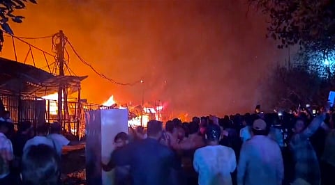 People gather as flames billow after a fire broke out at a furniture market, in Shastri Park, New Delhi, Saturday, May 23, 2026.