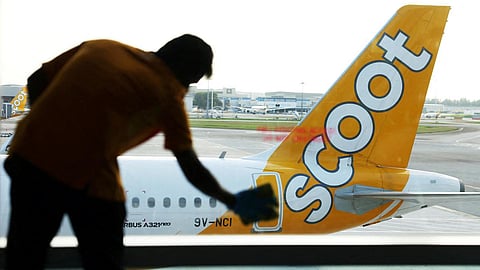A Scoot plane sits on the tarmac at an airport.