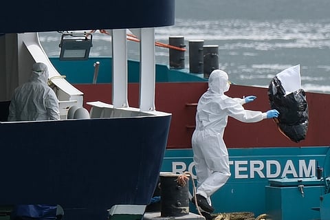 People in protective gear remove waste from the MV Hondius cruise ship after its arrival at the Port of Rotterdam, Netherlands, Monday, May 18, 2026.