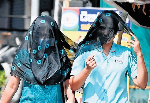 A woman uses a shawl to shield herself from the sun on Sunday.