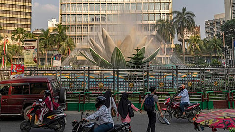 Vehicles and pedestrians pass by the Shapla Chattar fountain in front of Bangladesh Bank in Dhaka, Bangladesh, Wednesday, May 6, 2026.