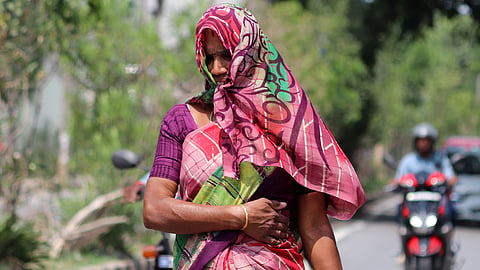 While yellow alert has been issued in Bengaluru expecting rains, a woman drapes herself as the sun remains harsh during the day, at Arekere on Sunday.