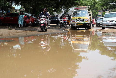 Motorists wade through stagnant rainwater after last night's rain in Vellalore, Coimbatore, on Monday.