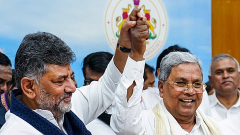 Karnataka Chief Minister Siddaramaiah and Deputy Chief Minister DK Shivakumar raise hands during a press conference after Siddaramaiah announced his resignation in Bengaluru, Thursday, May 28, 2026.