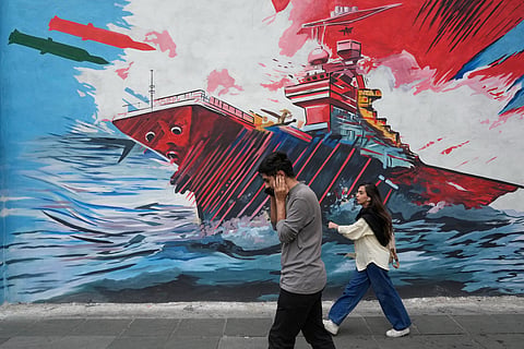 People walk past a mural depicting a U.S. aircraft carrier under missile attack in downtown Tehran, Iran, Sunday, May 17, 2026.