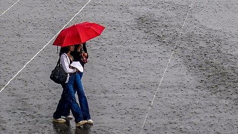 People cover themselves as they walk amid rainfall