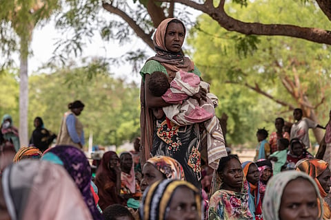 A woman holds her baby outside the registration center for new refugees on the outskirts of the Korsi Refugee Camp in Birao, Central African Republic, Thursday, March 26, 2026.