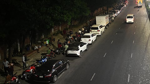 People queue up along a road to refuel their vehicles at a filling station in Dhaka on April 21, 2026, amid Bangladesh's fuel crisis triggered by the West Asia war.