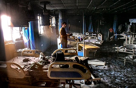 A man looks at the charred remains after a fire broke out in the ICU of a private hospital in Bihar's Muzaffarpur district, Thursday,
