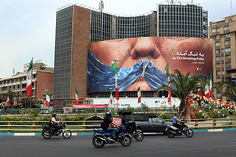 Iranians drive past a billboard featuring US President Donald Trump and the Strait of Hormuz, erected on Valiasr Square in Tehran May 28, 2026.