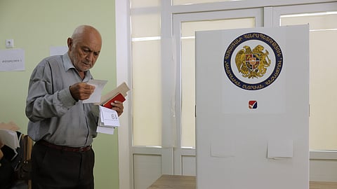 A man looks at his ballot at a polling station during the parliamentary election in Yerevan, Armenia, Sunday, June 7, 2026.
