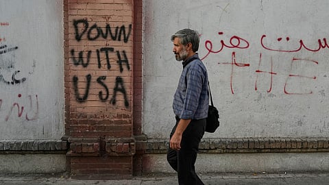A man walks past anti-US graffiti painted on the wall of the British Embassy in Tehran, Iran, Saturday, June 6, 2026.