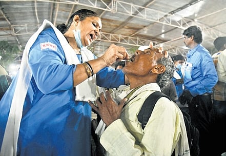 A volunteer administering fish prasadam to a patient.