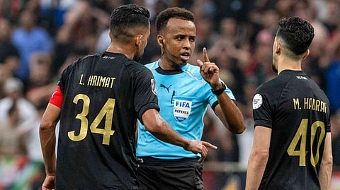 Referee Omar Artan, center, of Somalia, is confronted by players after calling a penalty kick during the CAF Champions League final soccer match between AS FAR Rabat and Mamelodi Sundowns, in Rabat, Morocco, Sunday, May 24, 2026.