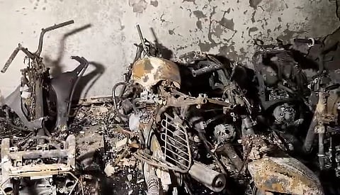 Charred remains of two-wheelers and bicycles are seen after a fire broke out in a five-storey residential building at Tughlakabad Extension area, in New Delhi, Friday, June 12, 2026.