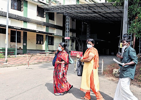 People wearing masks walk past a sign board at the Kozhikode Medical College Hospital warning against unauthorised entry into the isolation ward that was set up after Nipah was confirmed in Kozhikode
