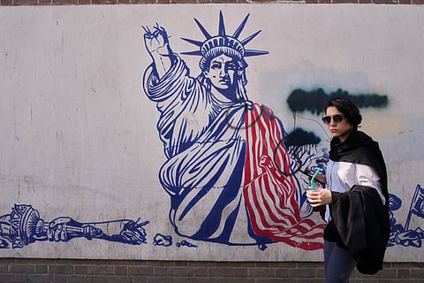 A woman walks past an anti-American mural on the wall of the former U.S. Embassy, now a museum, in Tehran, Iran, Friday, June 12, 2026.