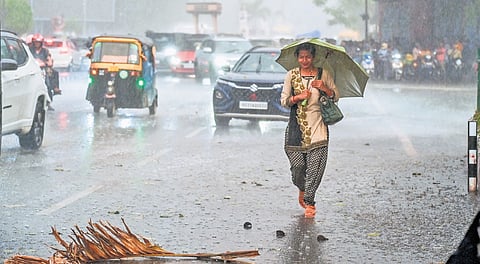A woman walks in the rain, as the city enjoys cool relief after a sudden downpour, in Bhubaneswar on Thursday