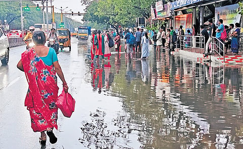 Stagnant water forces commuters to wait for buses on the main carriageway of Thirumangalam Main Road on Thursday