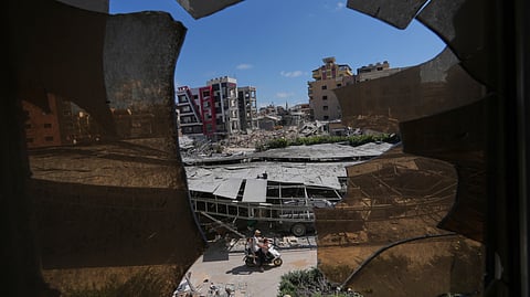 Buildings damaged by Israeli strikes are seen through shattered glass from the Jabal Amel Hospital in the southern port city of Tyre, Lebanon, Thursday, June 18, 2026.