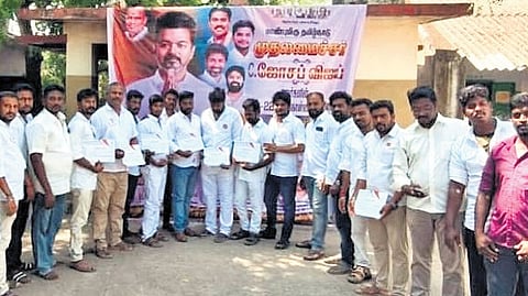 TVK cadre standing beside a Vijay poster inside a school in Uppiliyapuram.