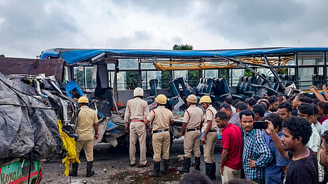 Police personnel and others gather near mangled remains of a bus after its collision with a truck on NH-27, at Ulladabri area, in Jalpaiguri district, West Bengal, Sunday, June 21, 2026.