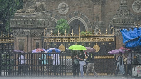 People open umbrellas amid the rain near Chhatrapati Shivaji Maharaj Terminus, in Mumbai.