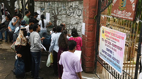 Aspirants wait outside a centre at Begumpet in Hyderabad on Sunday.