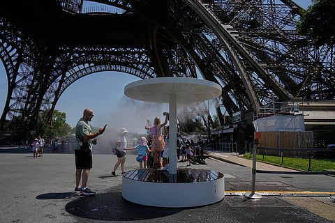 People cool off in a water spray at the Eiffel Tower in Paris, Sunday, June 21, 2026.
