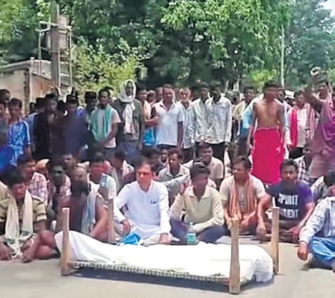 Villagers staging road blockade with the deceased farmer’s body at Jadamunda in Komna on Tuesday
