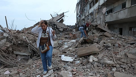 Residents walk among the rubble of building damaged in earthquakes the previous day in Catia La Mar, Venezuela on Thursday